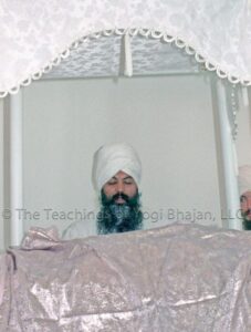 Yogi Bhajan sitting behind the Siri Guru Granth Sahib