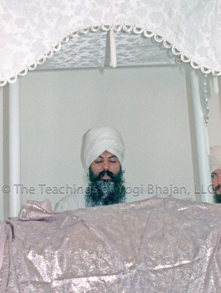 Yogi Bhajan sitting behind the Siri Guru Granth Sahib
